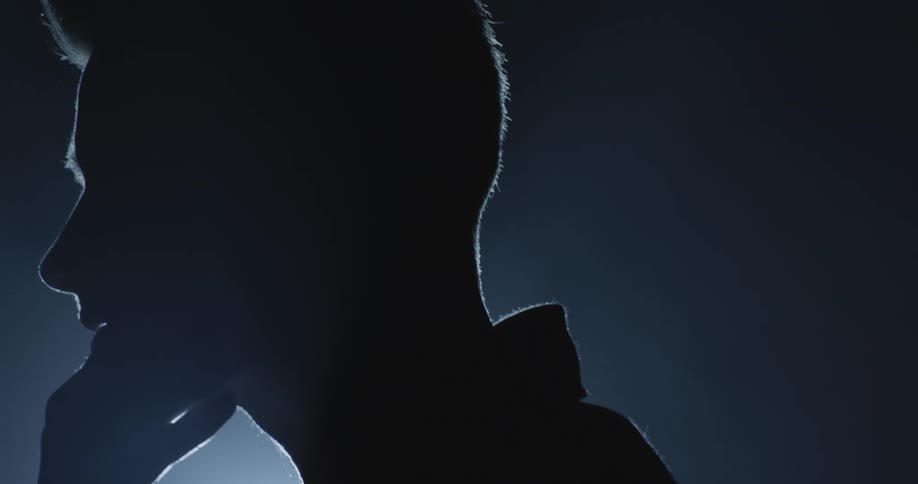 Silhouette of the face of a young man in front of a spotlight