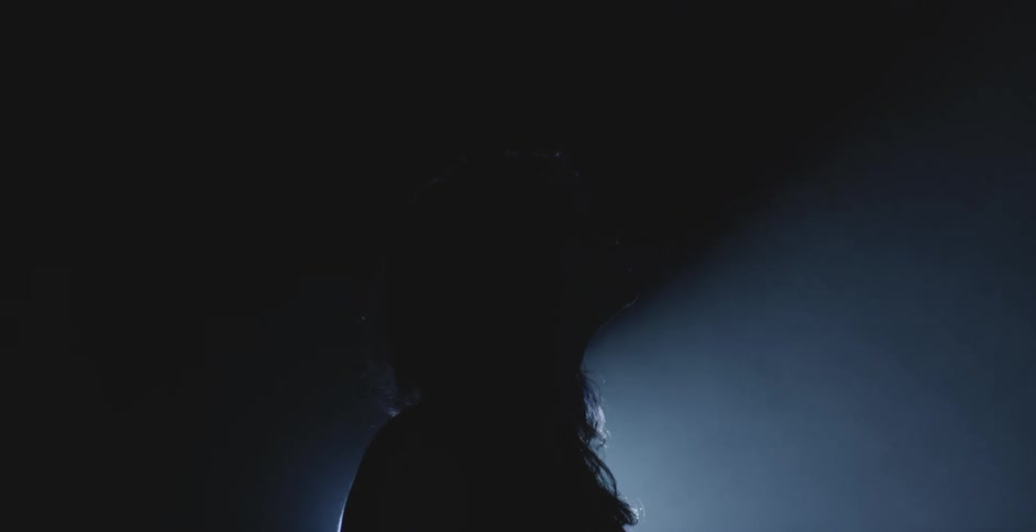 A female standing in the dark with smoke and light blue lighting