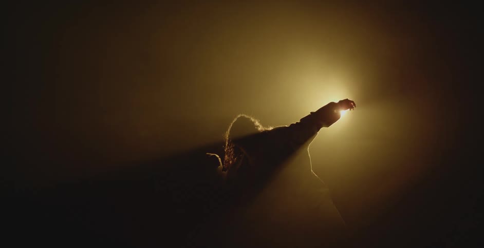 Silhouette of a woman dancing in front of a spotlight