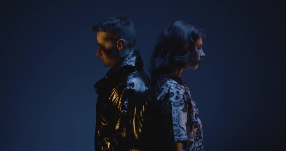 A man and woman stand back to back