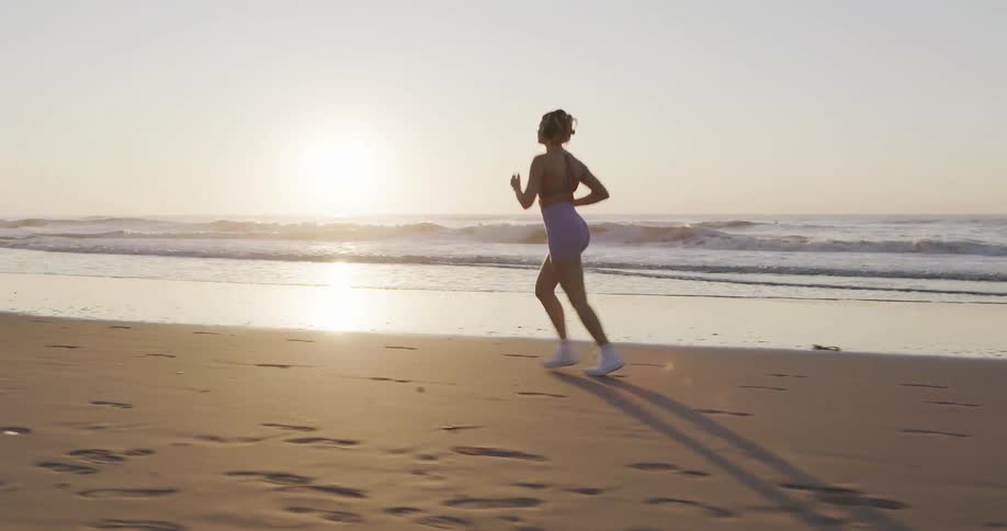 A woman exercising on the beach during sunset