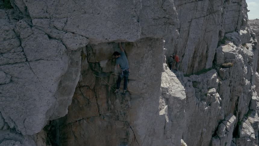 A person climbing a rocky mountain during the day on an adventure