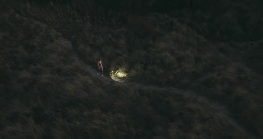 Person walks along that nature trail with flashlight in the dark