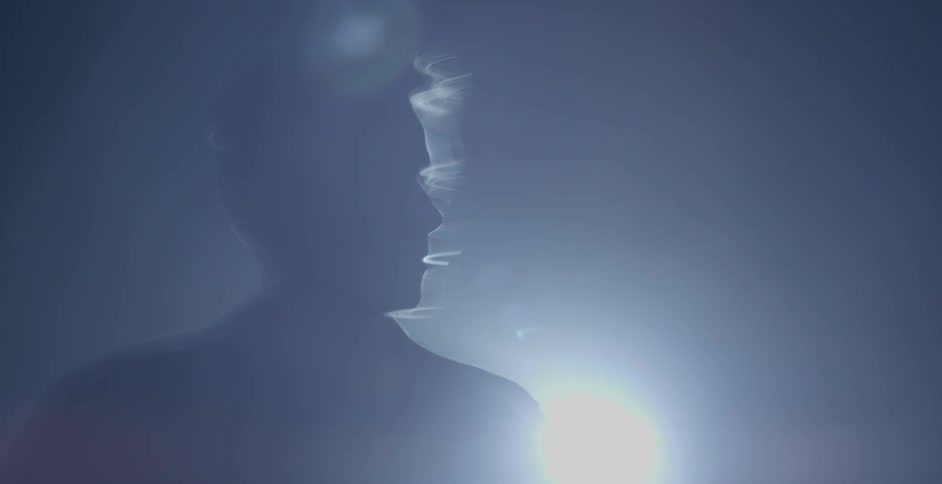 A man moves around the spotlight in the dark
