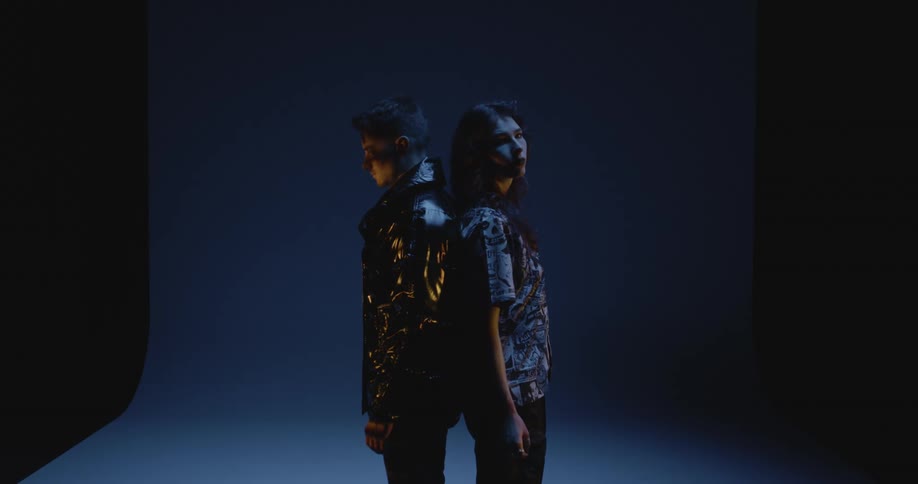 Two models stand back to back in a studio