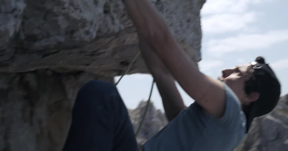 A man climbing to the top of a mountain during a sunny day