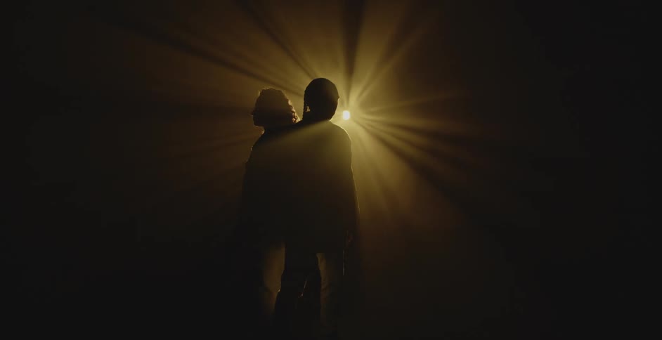 A yellow light shines on the people in the dark