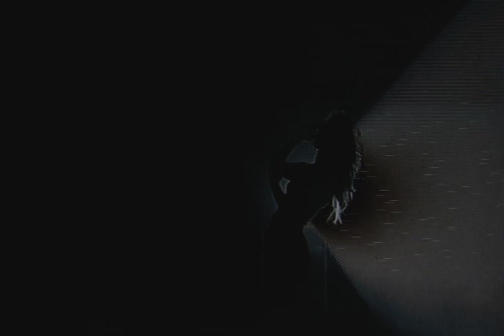 Silhouette of a woman in front of a spotlight with vhs video distortion