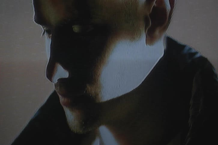 A male from the neck up with shadows and lighting on his face