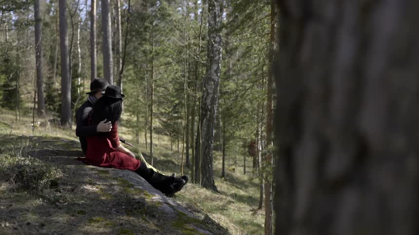 Man sitting next to woman massaging her arm in wooded area