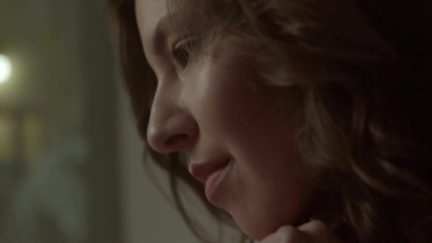 A woman holding a pen and some paper is thinking something over