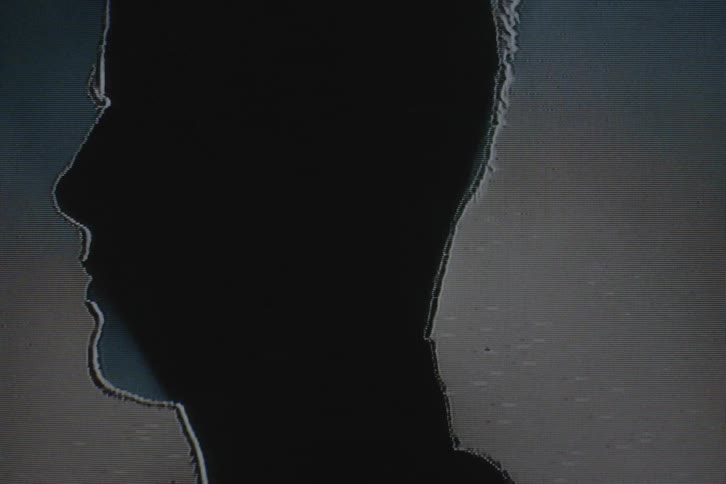 Silhouette of a man in front of a spotlight on vhs video distortion
