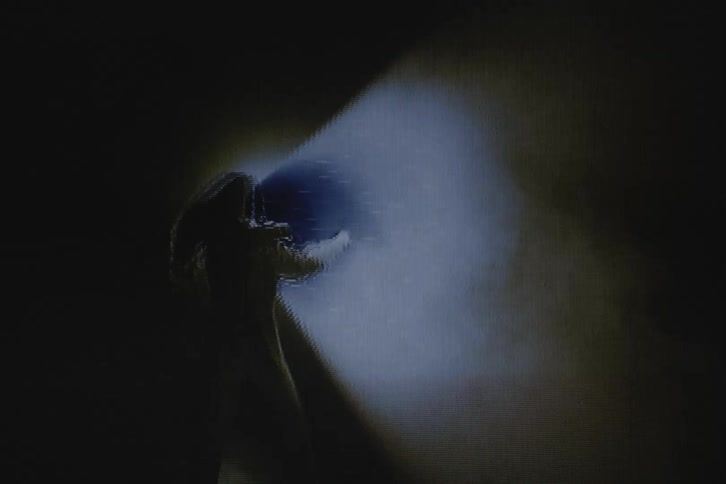 Silhouette of a woman in front of a spotlight with vhs video distortion