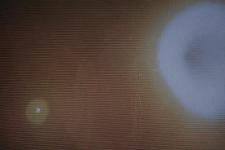 Two people standing in the dark with bright light shining on them