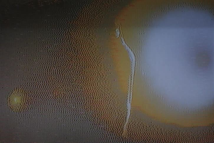 An old recording of a person and behind them a flare of light passes to the sides