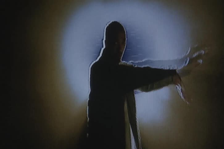 A man is dancing in the dark under a spotlight