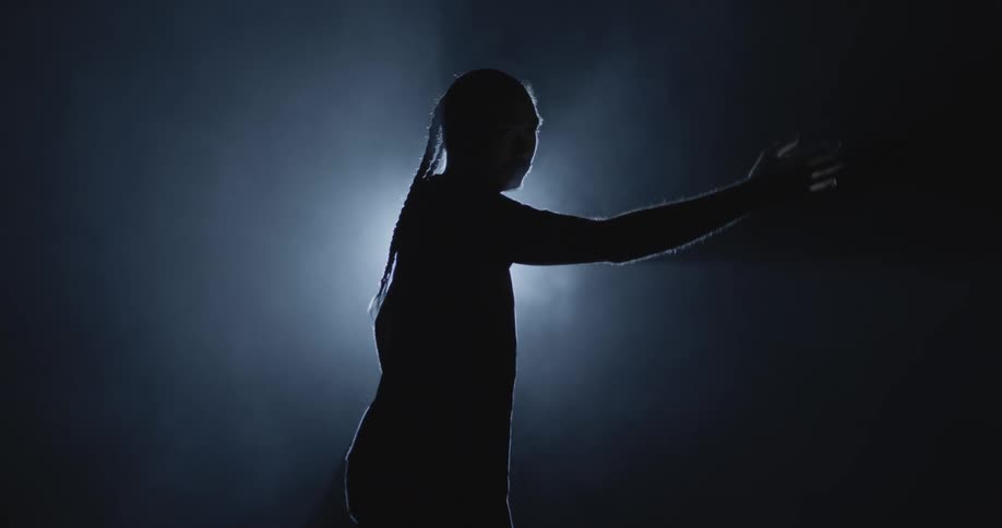 A person illuminated by a white light in a dark room