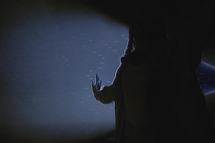 Two dancers perform in front of a spotlight and the footage is distorted