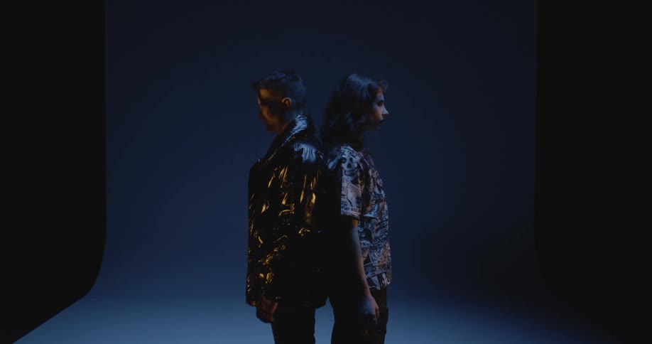 Two models backtoback on a studio under moving lights