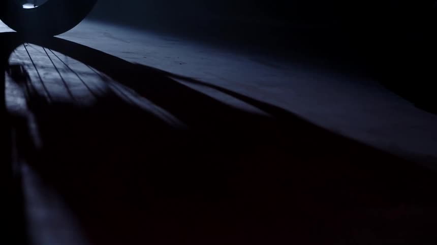 Shadow of a bicycle wheel inside a dimly lit room