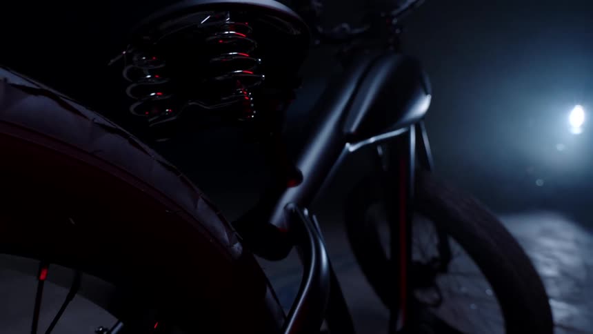 A black bicycle in a dark environment lit by a spotlight