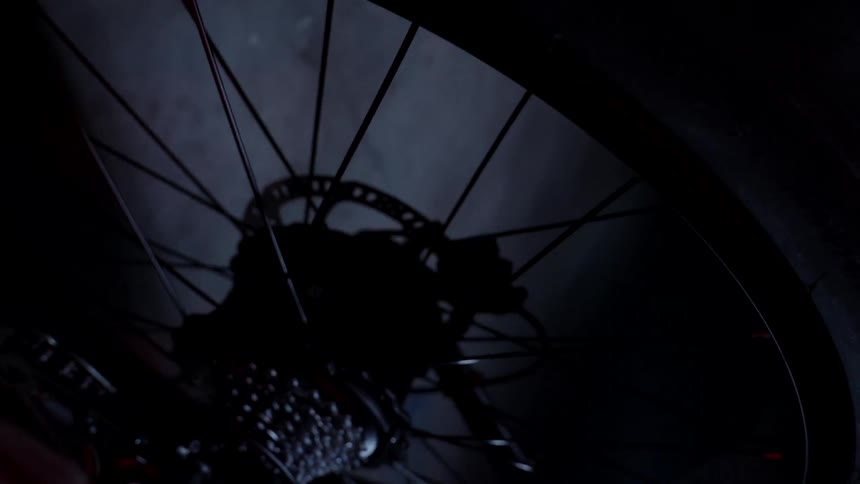 The camera spirals away from the wheel of a bicycle in a garage space