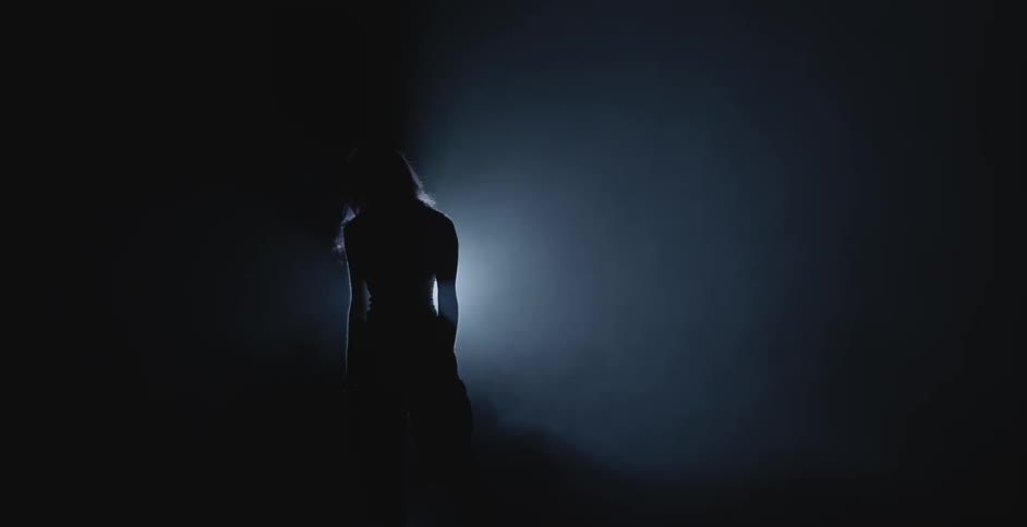 Silhouette of a performer dancing in front of a spotlight