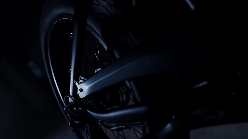 Light gleams off of the frame of a bicycle in a dark garage