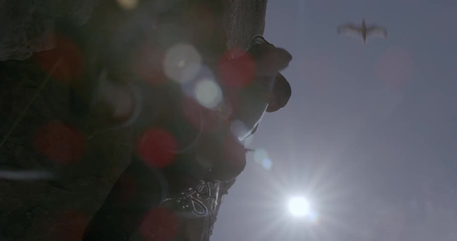 Sun shines over a man climbing a rock wall in the mountain
