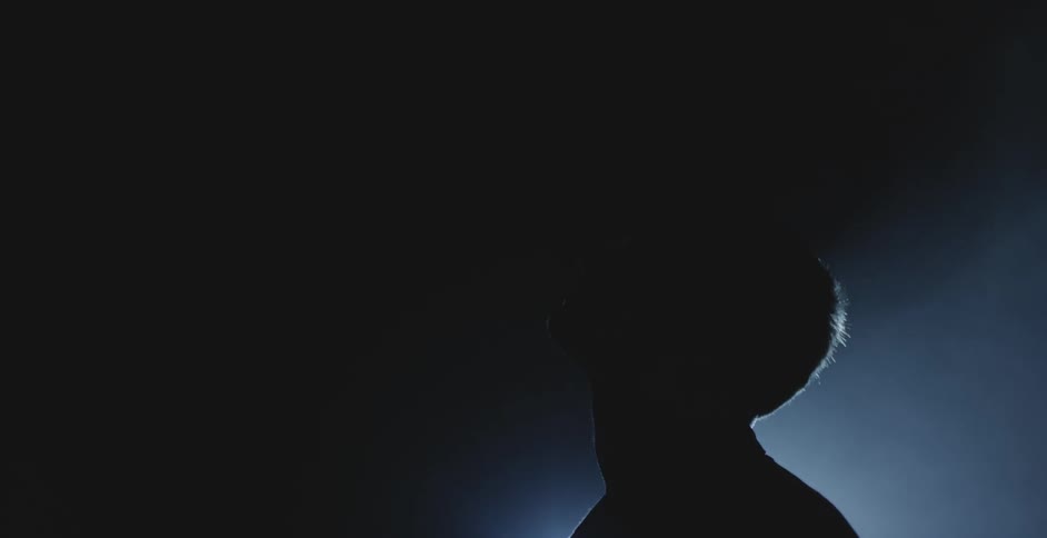 Silhouette of a man in a dark room with spotlights