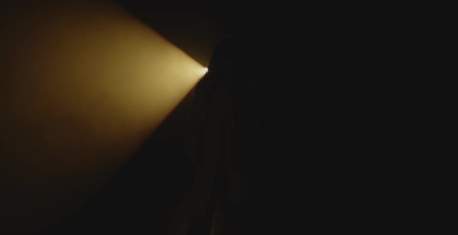 A woman walks in front of the spotlight