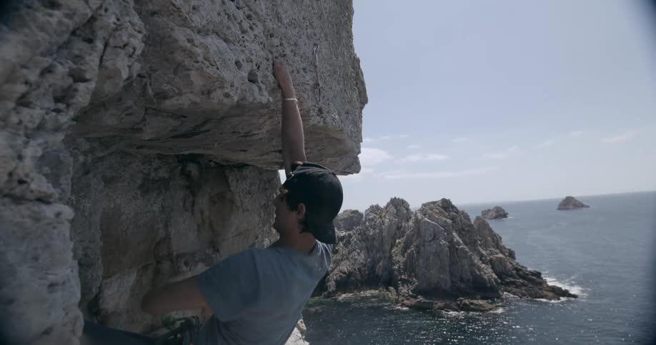 A man is mountain climbing by the shore