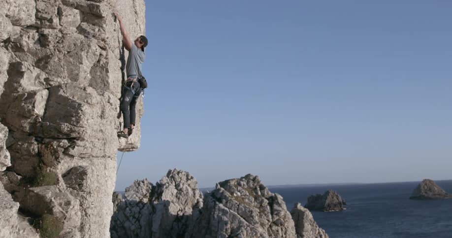 Man climbs seaside cliff on a sunny day