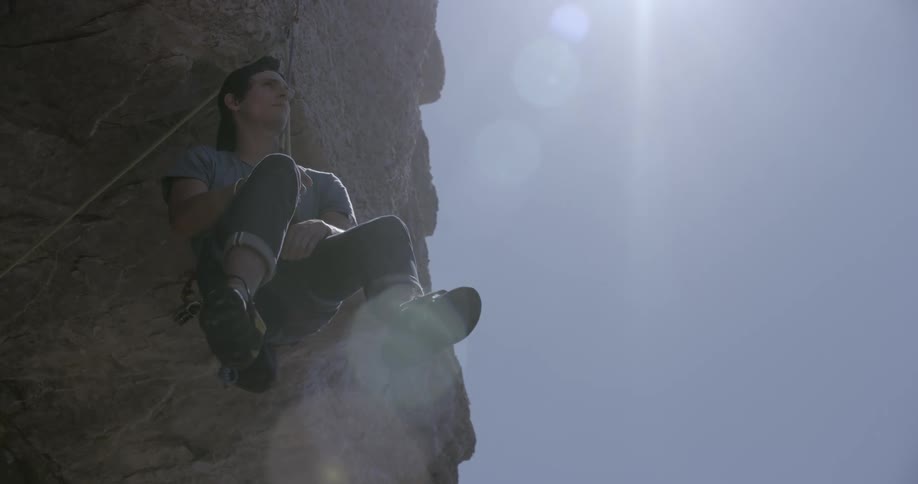 A man hanging from a rope on a rocky mountain
