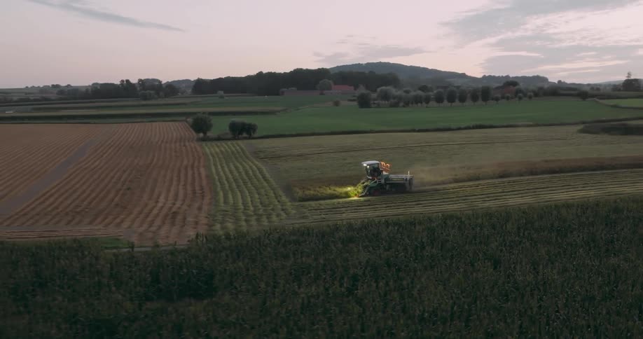 Aerial view of a combine harvesting a field at evening