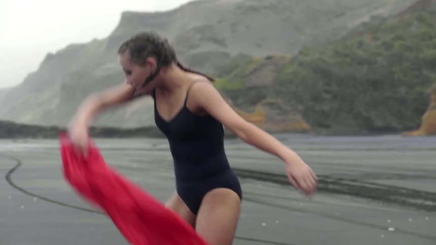 A graceful girl matches the energy of the wind with her expressive beach dance.