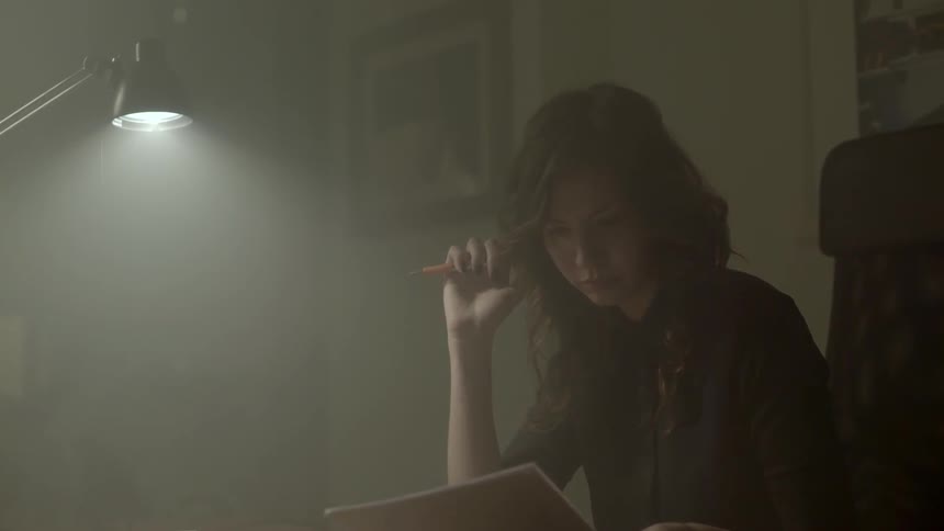 A quiet professional reflects on confidential business data while reviewing prints at work.