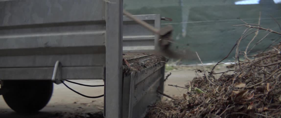 A man sweeping dirt and branches out of the back of his truck