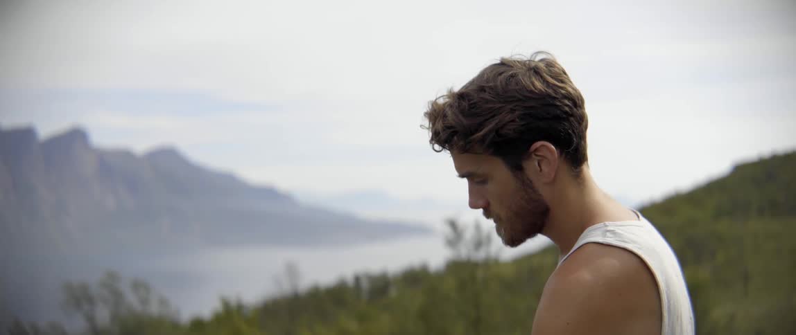 A melancholic explorer pauses to clear his mind during a challenging solo wilderness trek.