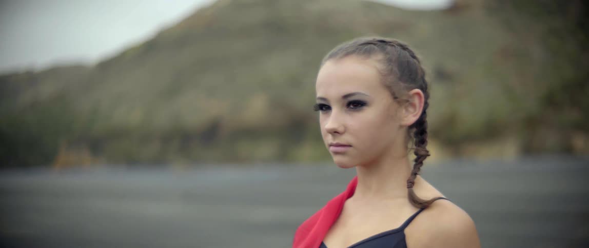 A focused young dancer prepares her mind before a creative performance by the sea.