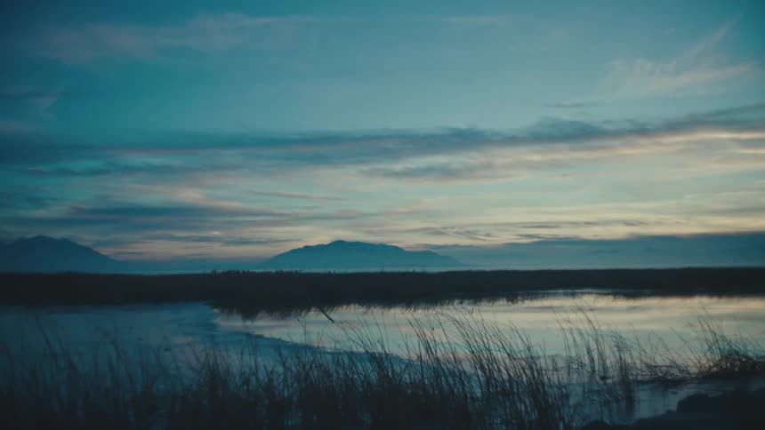 Sky reflecting on a lake next to the mountains
