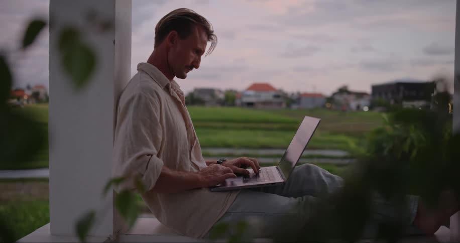A man opens his laptop on the porch