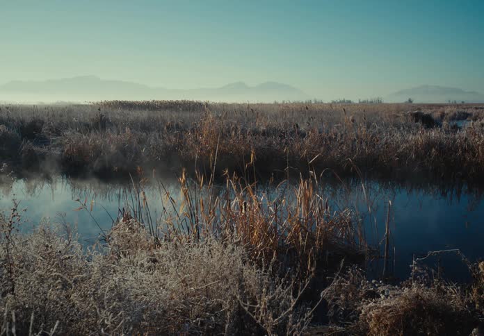 Sky reflects on a lake in the plains next to the mountains