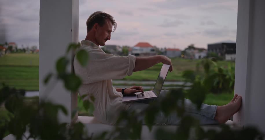 A man working on a laptop on the balcony
