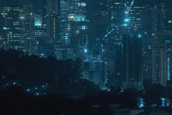 Skyscrapers constructed and going up simultaneously in a city skyline at night