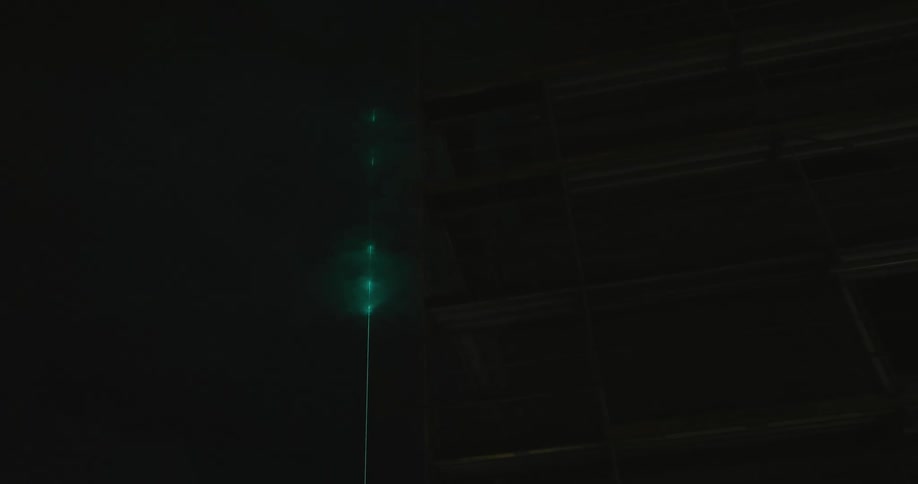 Green laser shines through the clouds at night