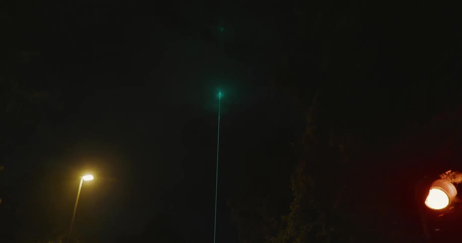 Green laser shines through the clouds at night