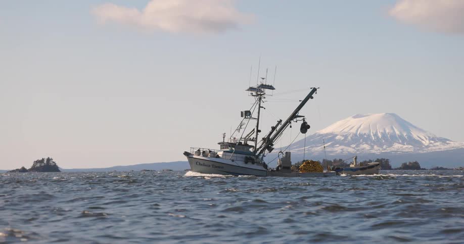 A commercial fishing boat is dragging a skiff in the ocean
