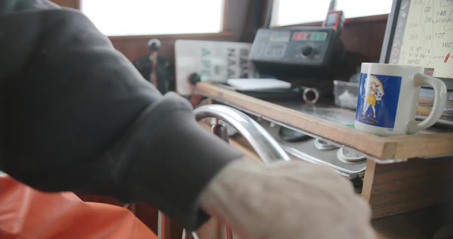 Captain turning a fishing boat wheel
