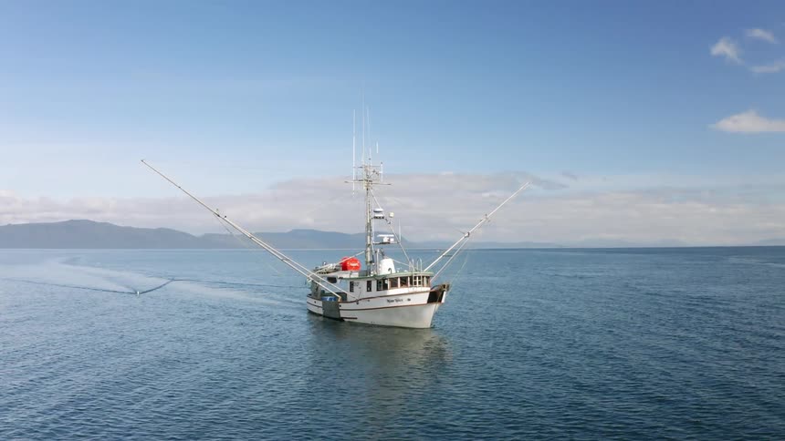Aerial view of a fishing boat dragging fishing lines in the ocean